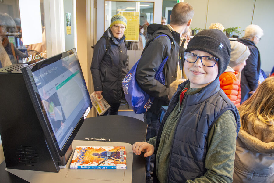 Gutt registrerer bok på automat