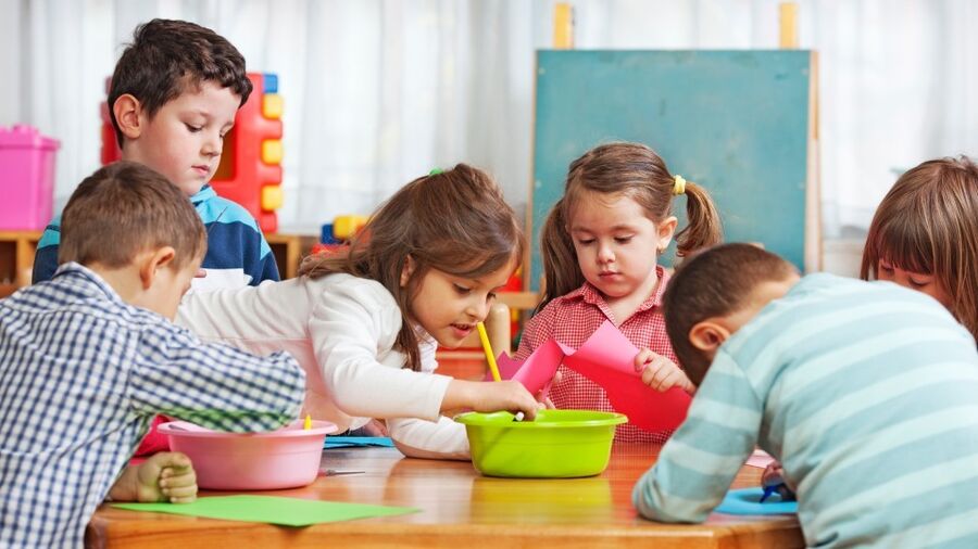 Barnehagebarn tegner ved et bord