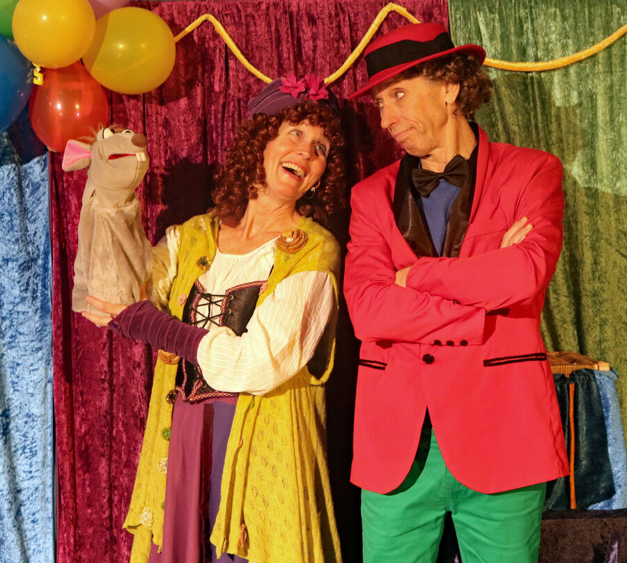 Kvinne med hånddukke og en mann, begge i kostymer på scenen