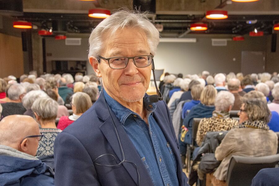 Portrett av mann med mange  tilhørere som sitter på stolrekkene bak