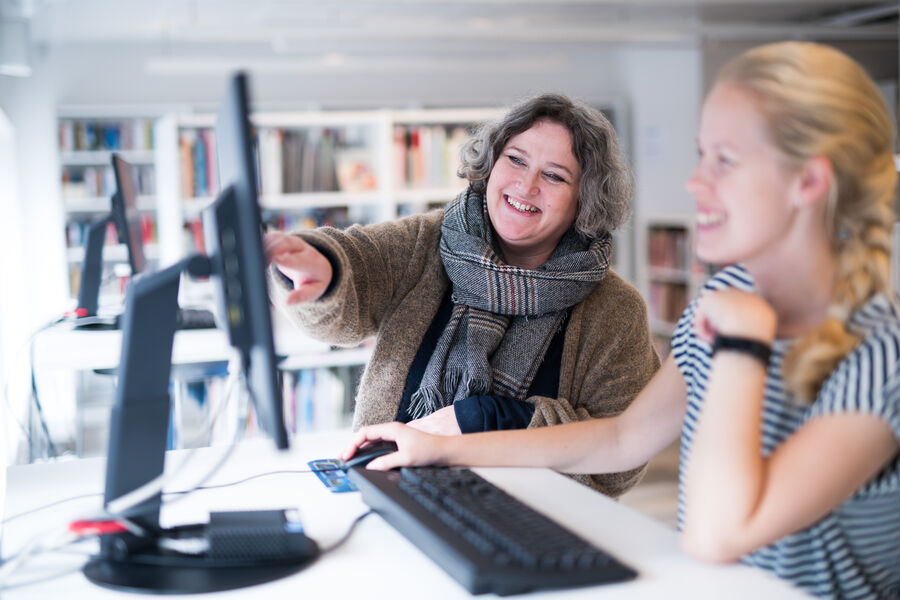 En dame hjelper en annen dame med en pc